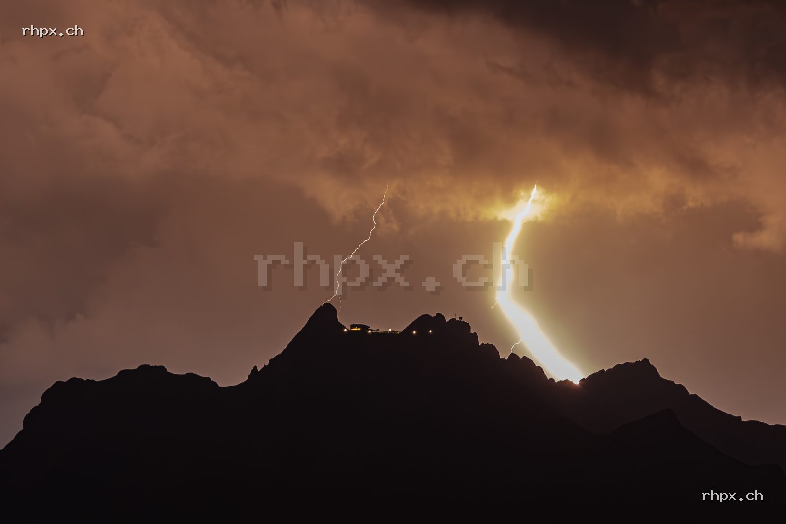 Blitz über dem Pilatus mit dunkler Bergsilhouette vor warm leuchtenden Gewitterwolken
