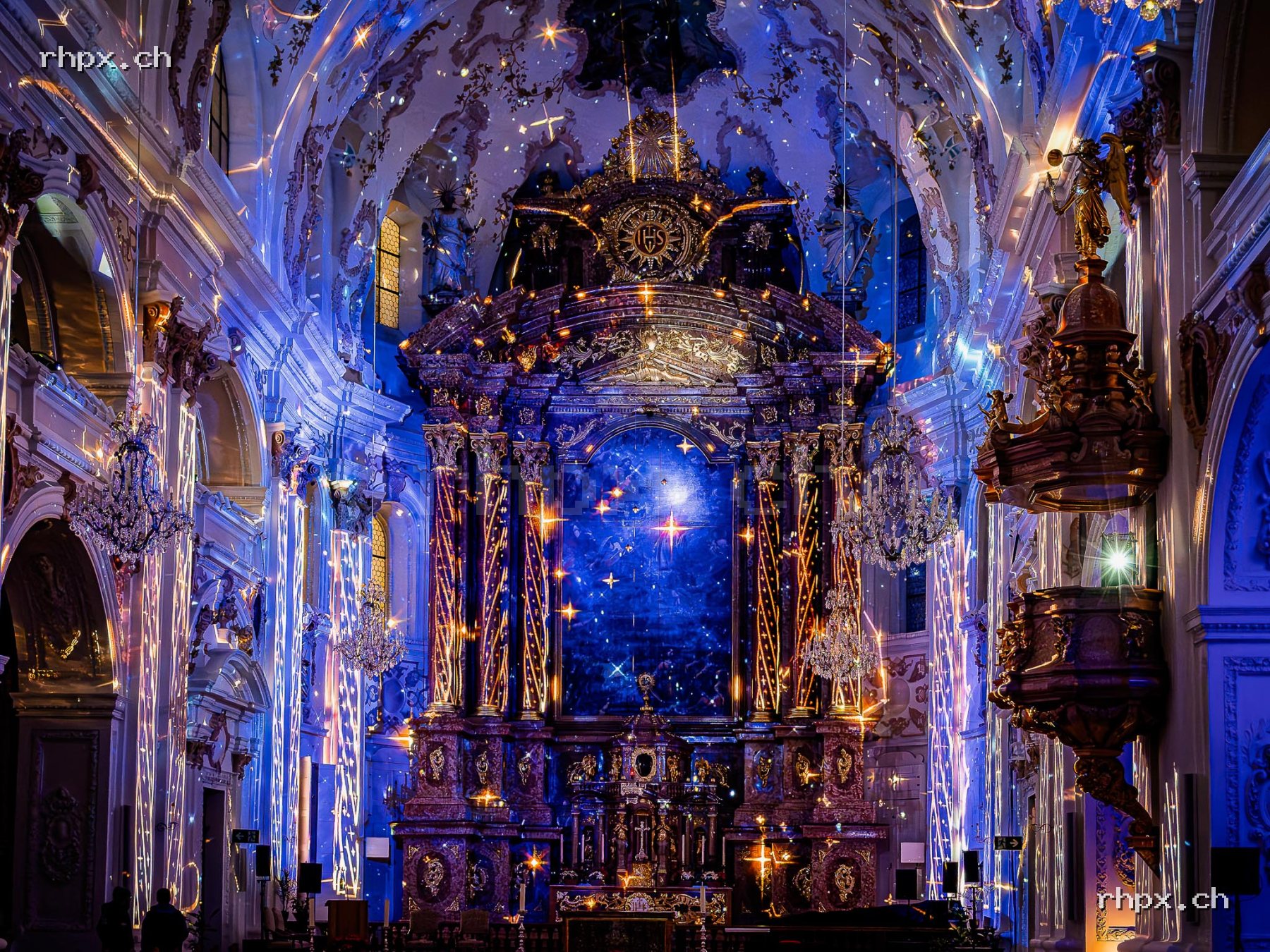 Interior of the Jesuit Church in Lucerne with blue and golden light projections on altar, walls and ceiling.