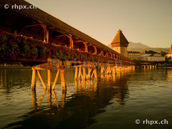 Historische Kapellbrücke mit Blumenschmuck und Wasserturm in Luzern am Abend