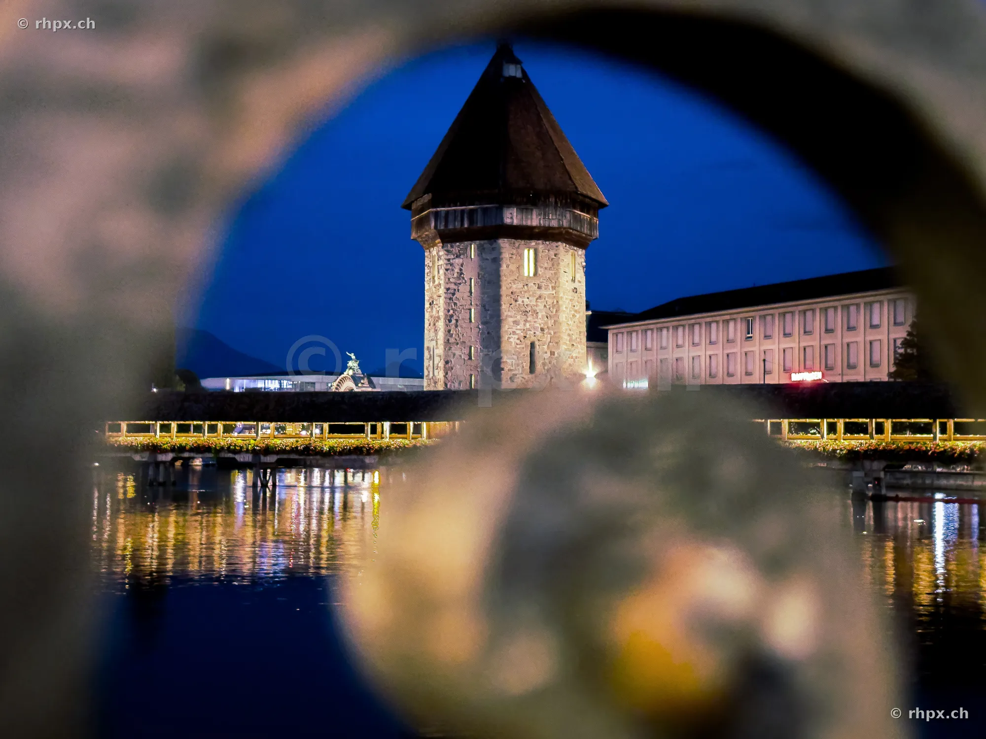 The Water Tower of the Chapel Bridge in Lucerne at twilight, viewed through a stone opening