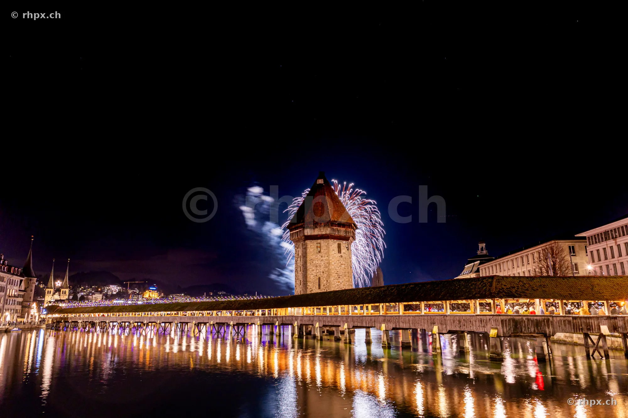 Night shot of the Chapel Bridge in Lucerne with fireworks in the night sky