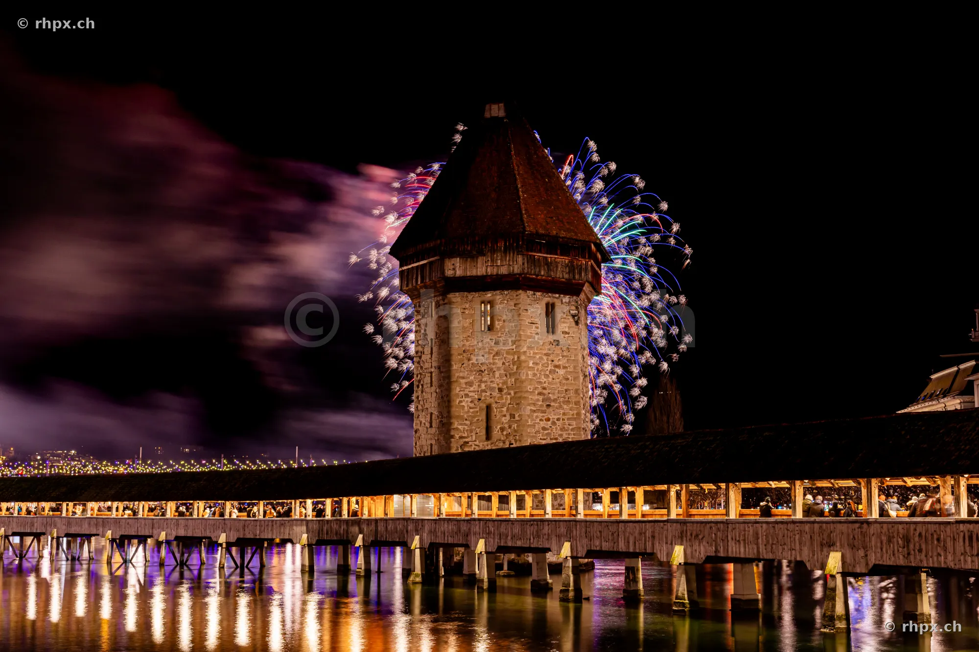 The Wasserturm of the Chapel Bridge in Lucerne during the 2024 New Year's fireworks at night.