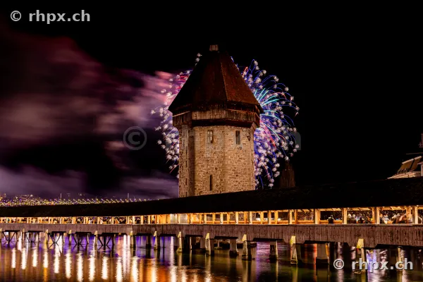 The Wasserturm of the Chapel Bridge in Lucerne during the 2024 New Year's fireworks at night.