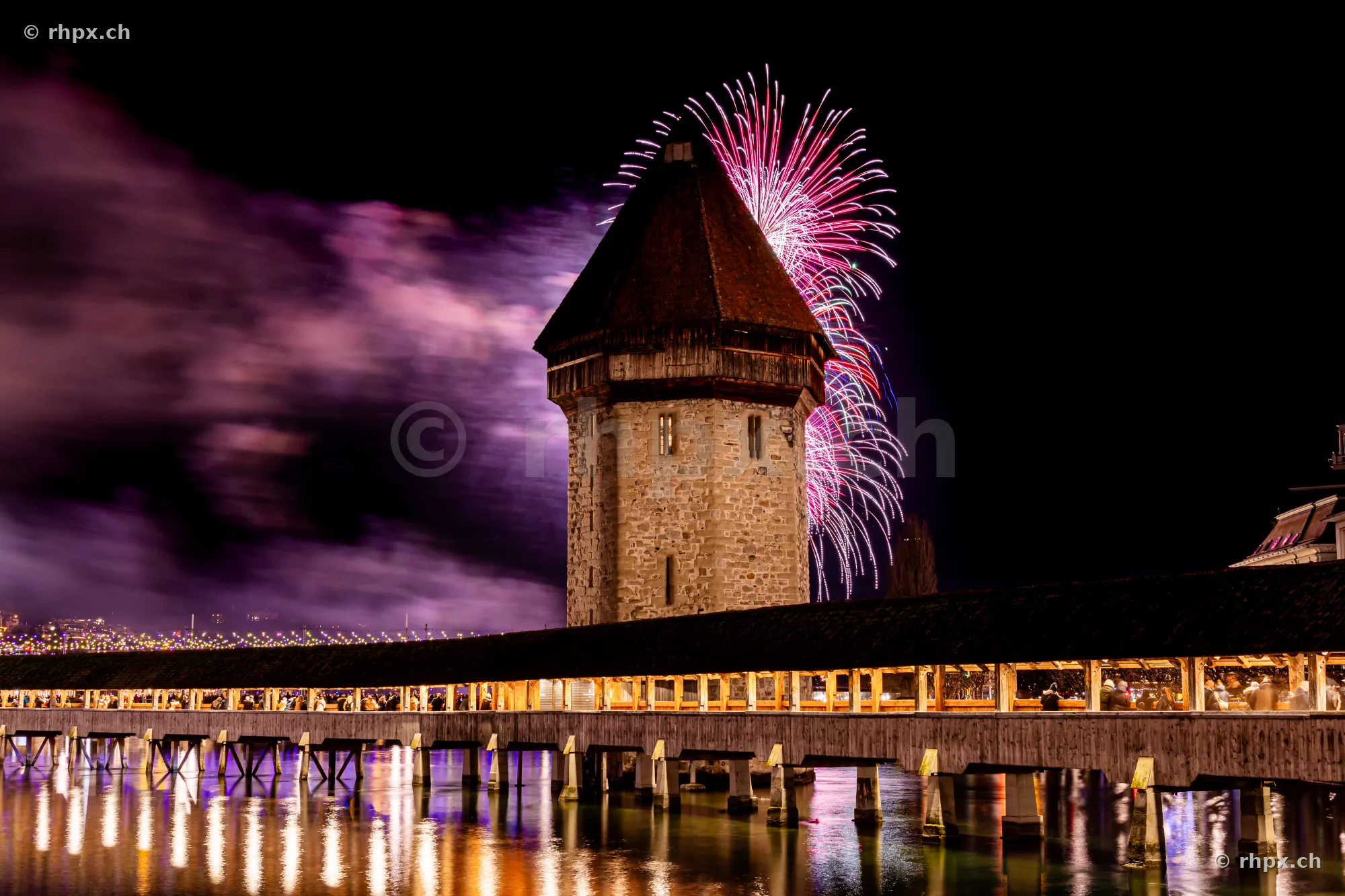 The illuminated water tower of the Chapel Bridge in Lucerne against New Year fireworks in 2024