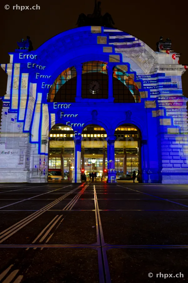 Blaue Lichtprojektion mit Schriftzug Error an der Fassade des Bahnhofs Luzern.