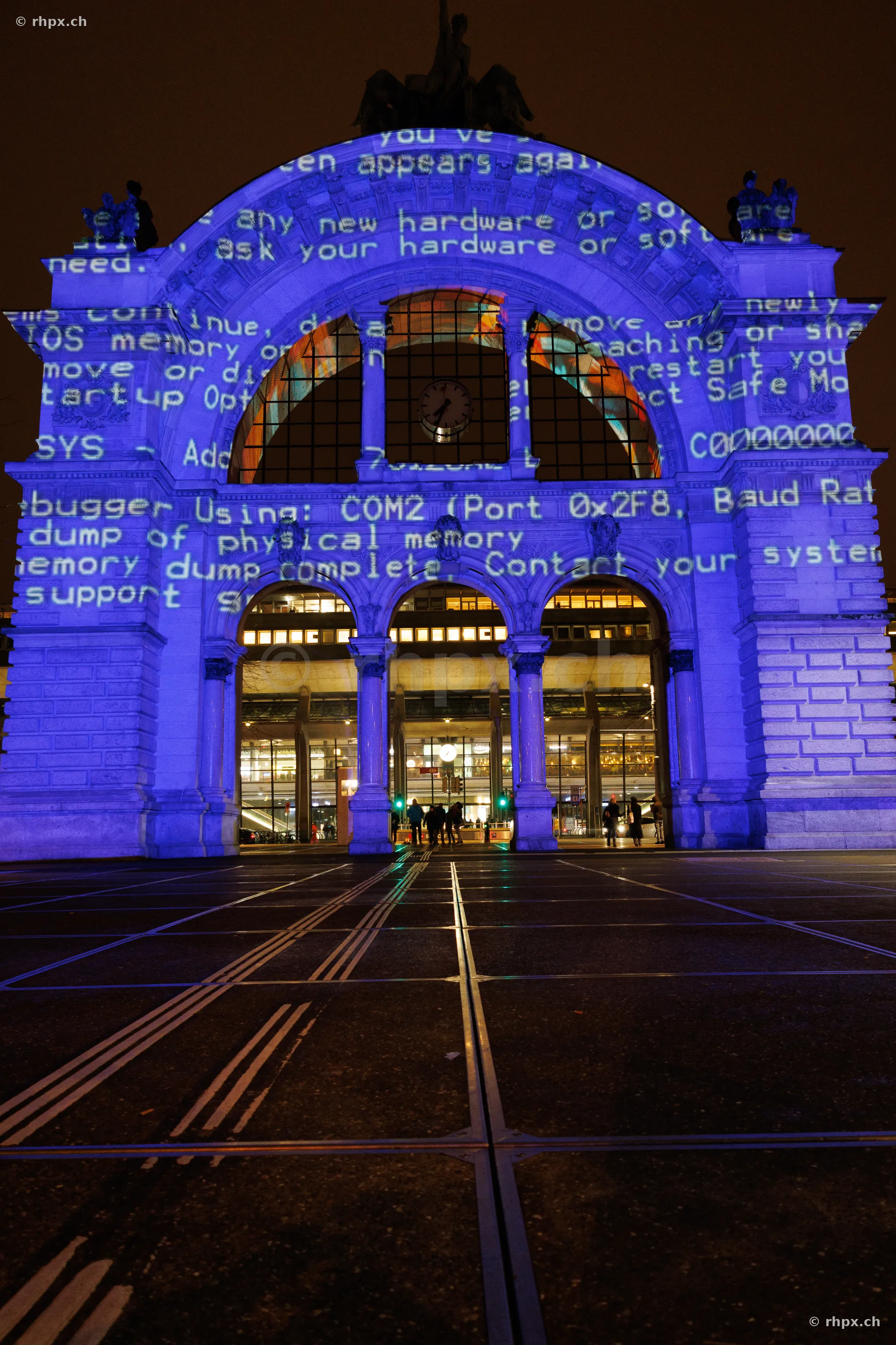 Portal of Lucerne train station with blue computer code projection during Lilu Light Festival 2024