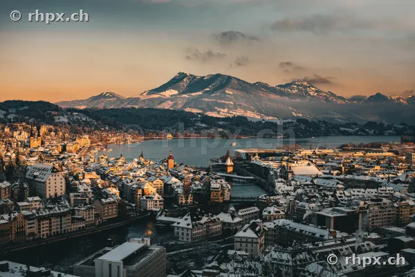 Vogelperspektive auf die verschneite Stadt Luzern, den Vierwaldstättersee und das Rigi-Massiv im Hintergrund