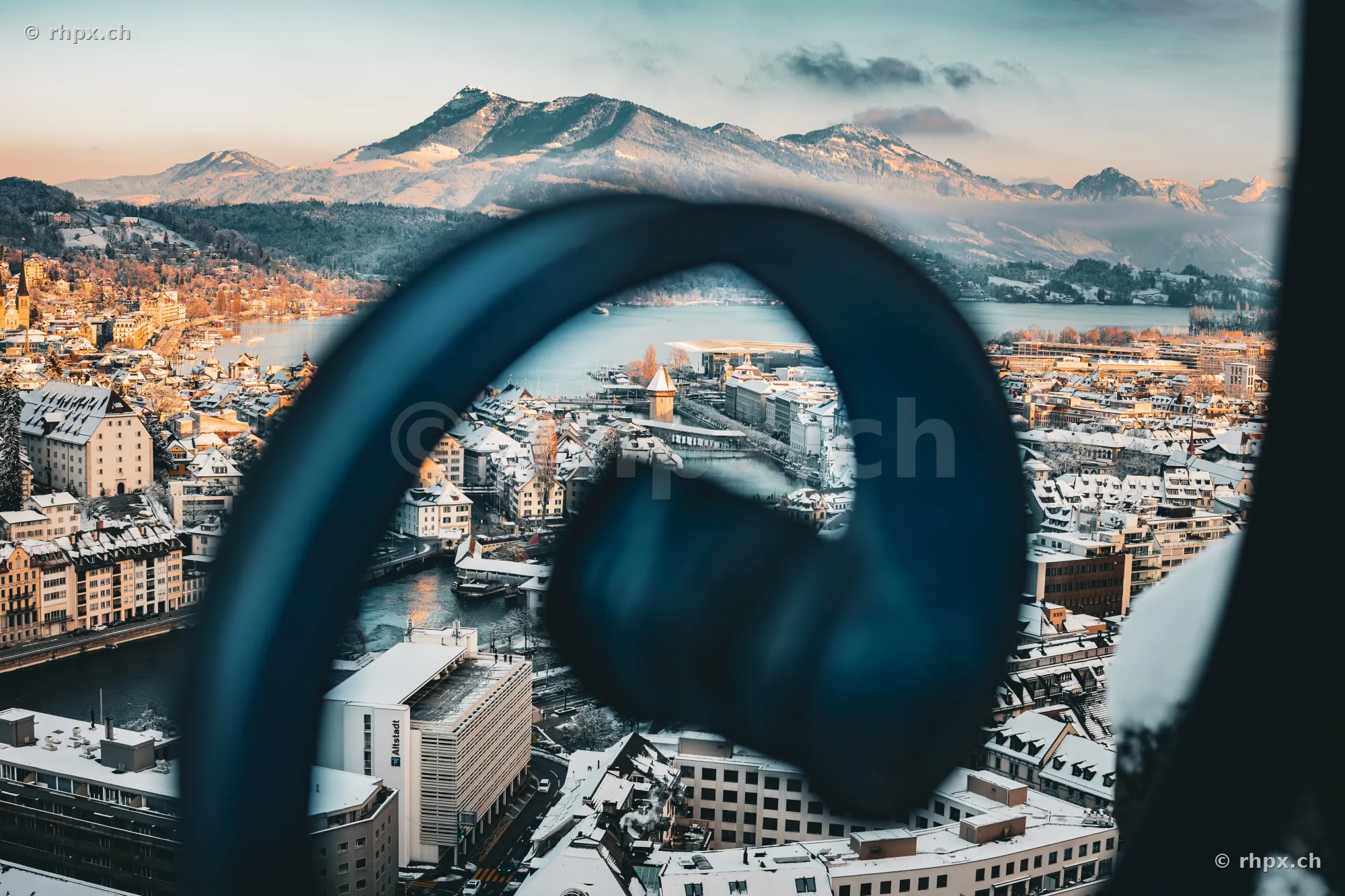 Snow-covered old town of Lucerne with Chapel Bridge in the background, seen through blurred headphones in the foreground