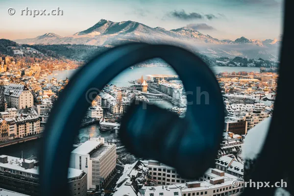 Verschneite Altstadt von Luzern mit Kapellbrücke im Hintergrund, gesehen durch einen unscharfen Kopfhörer im Vordergrund