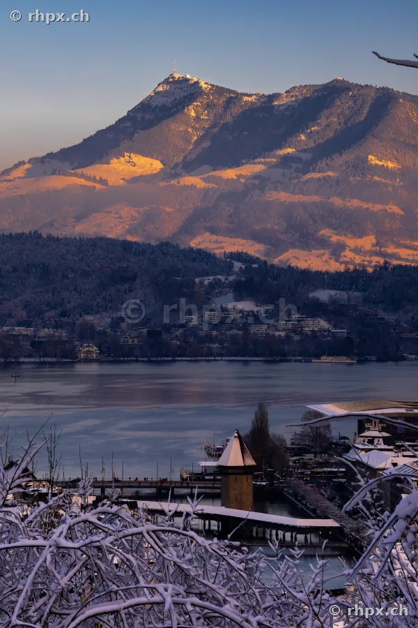 Blick auf den verschneiten Pilatus über dem Vierwaldstättersee und der Stadt Luzern im Abendlicht