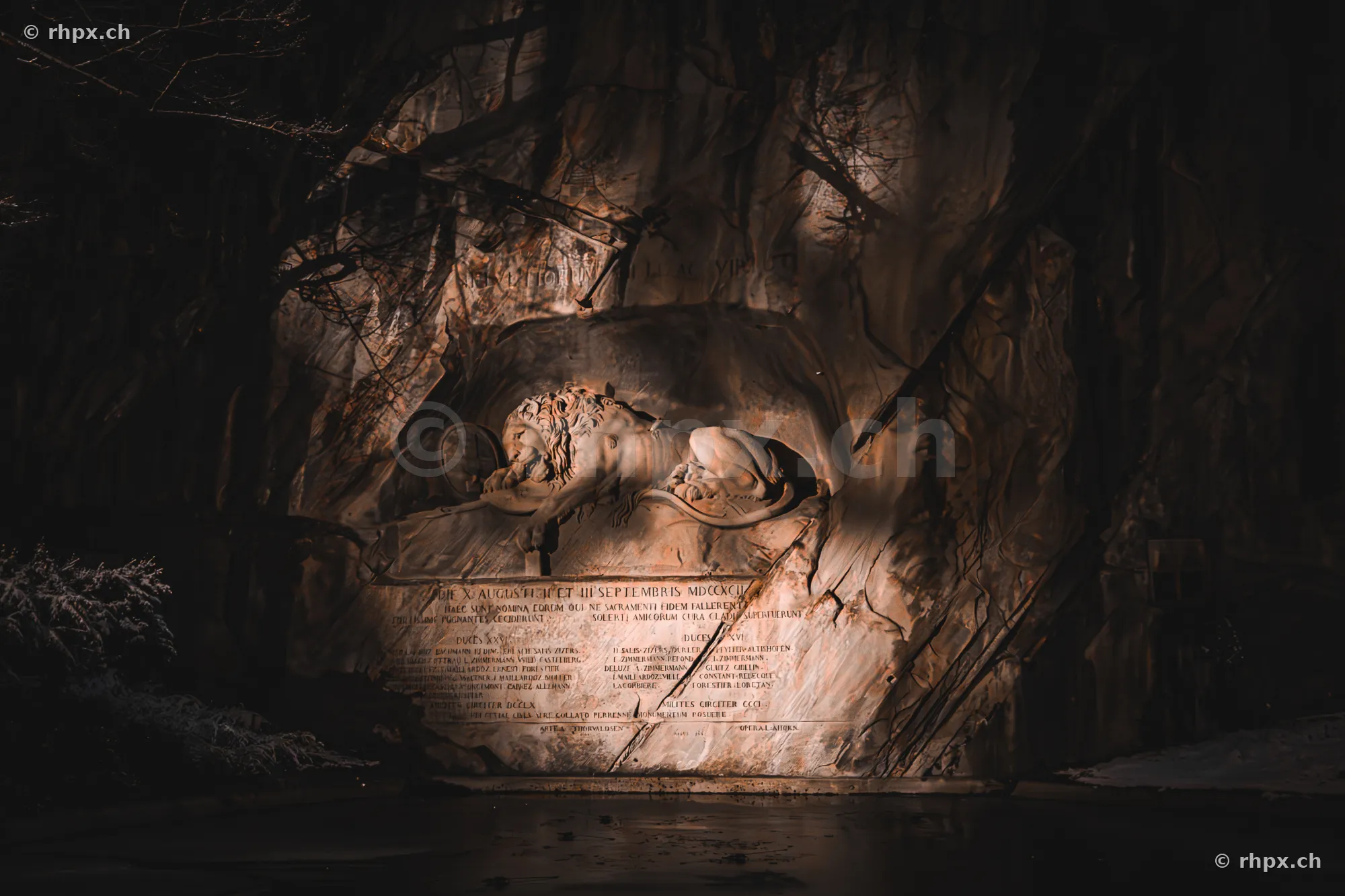 The Lion Monument in Lucerne illuminated at night in front of a rock face