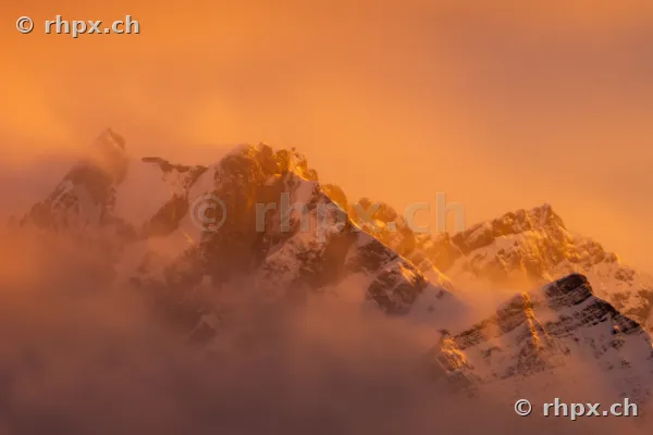 Der schneebedeckte Gipfel des Pilatus in goldenem Licht eingebettet in Wolken