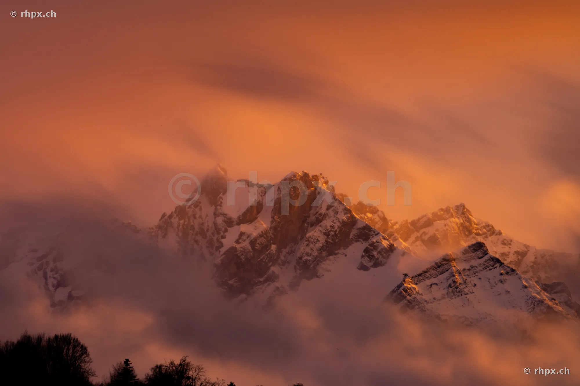 Snow-covered Mount Pilatus at sunset surrounded by moving clouds