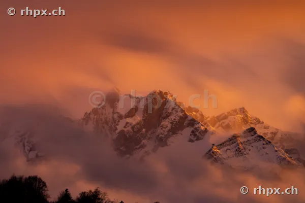Der schneebedeckte Pilatus bei Sonnenuntergang umhüllt von Nebelschwaden
