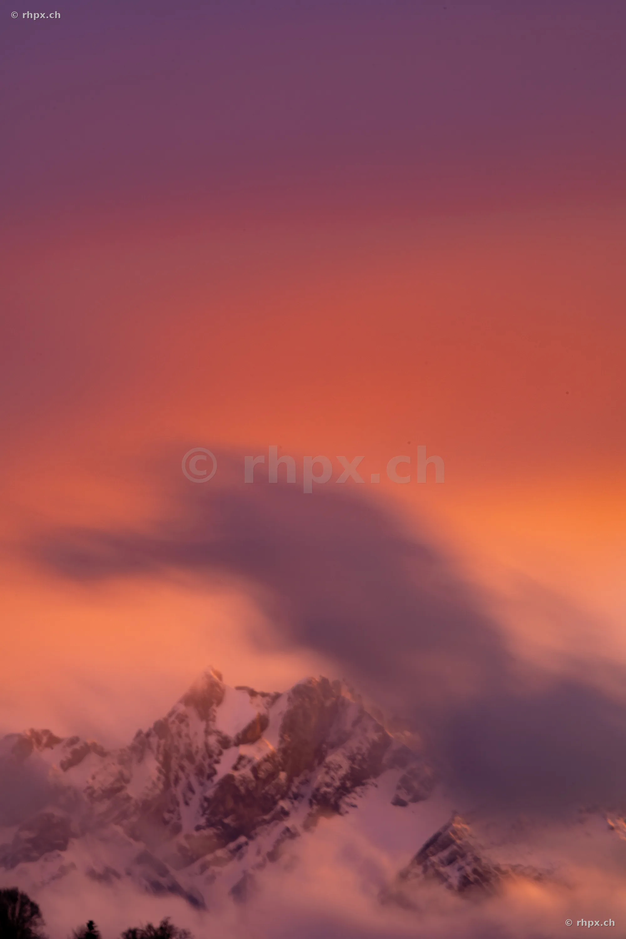 Snow-covered Mount Pilatus in warm evening light with moving clouds