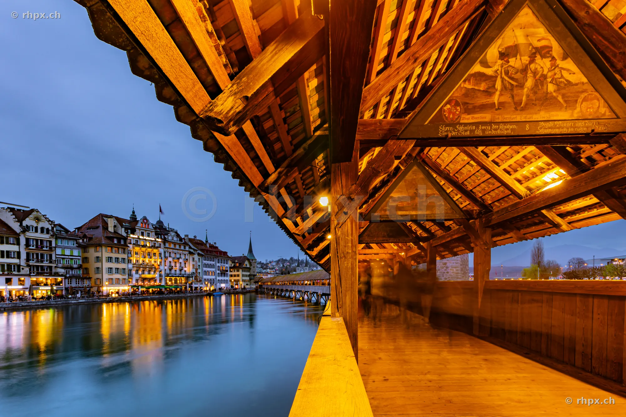 Interior view of the Chapel Bridge in Lucerne at twilight overlooking the illuminated old town