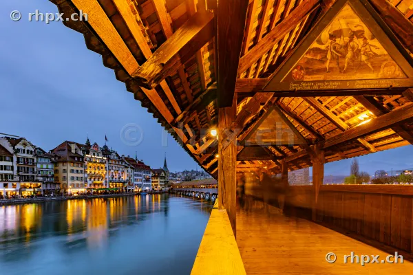 Innenansicht der Kapellbrücke in Luzern bei Dämmerung mit Blick auf die beleuchtete Altstadt