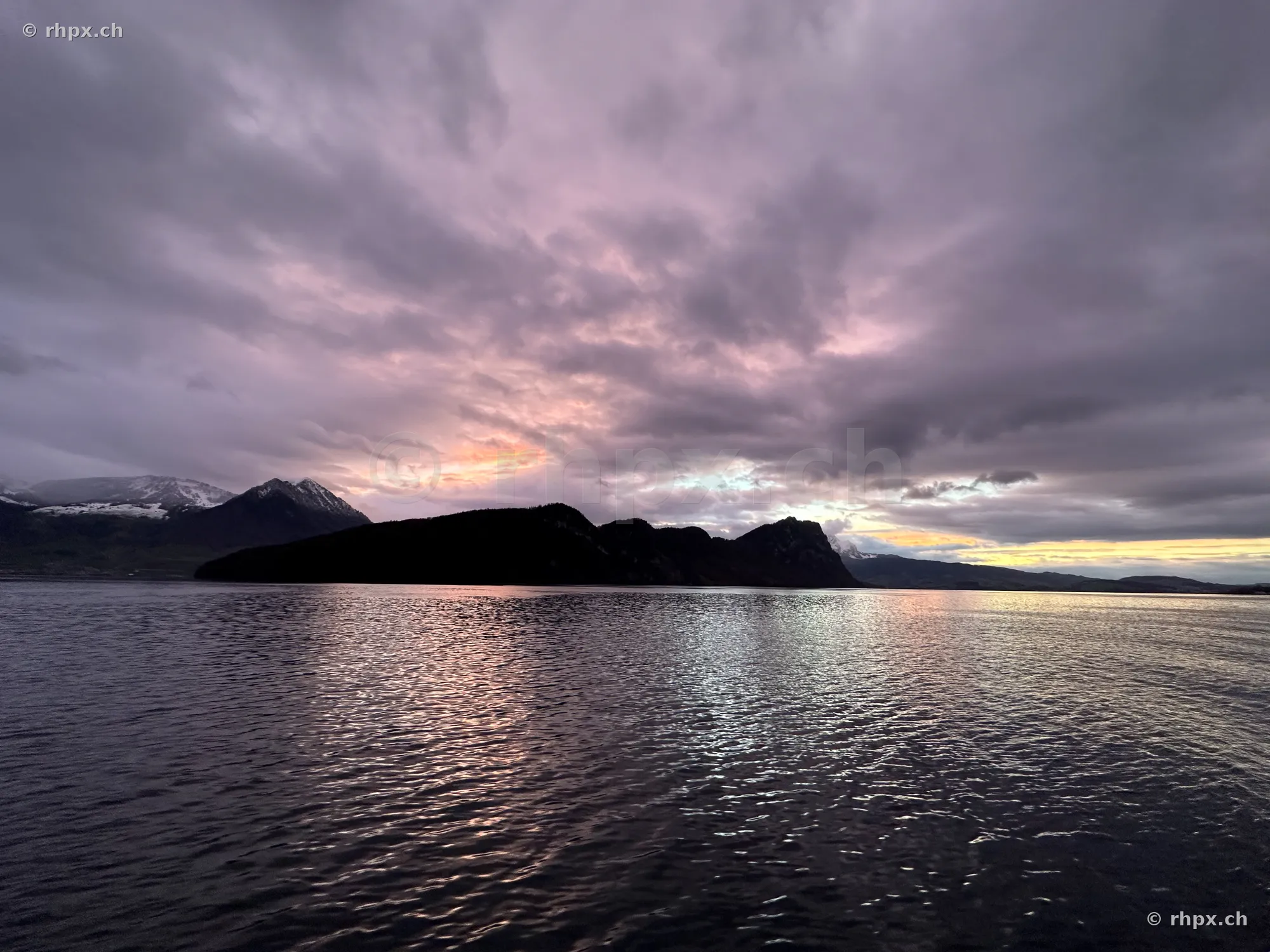 View across Lake Lucerne at twilight with the silhouette of Bürgenstock mountain