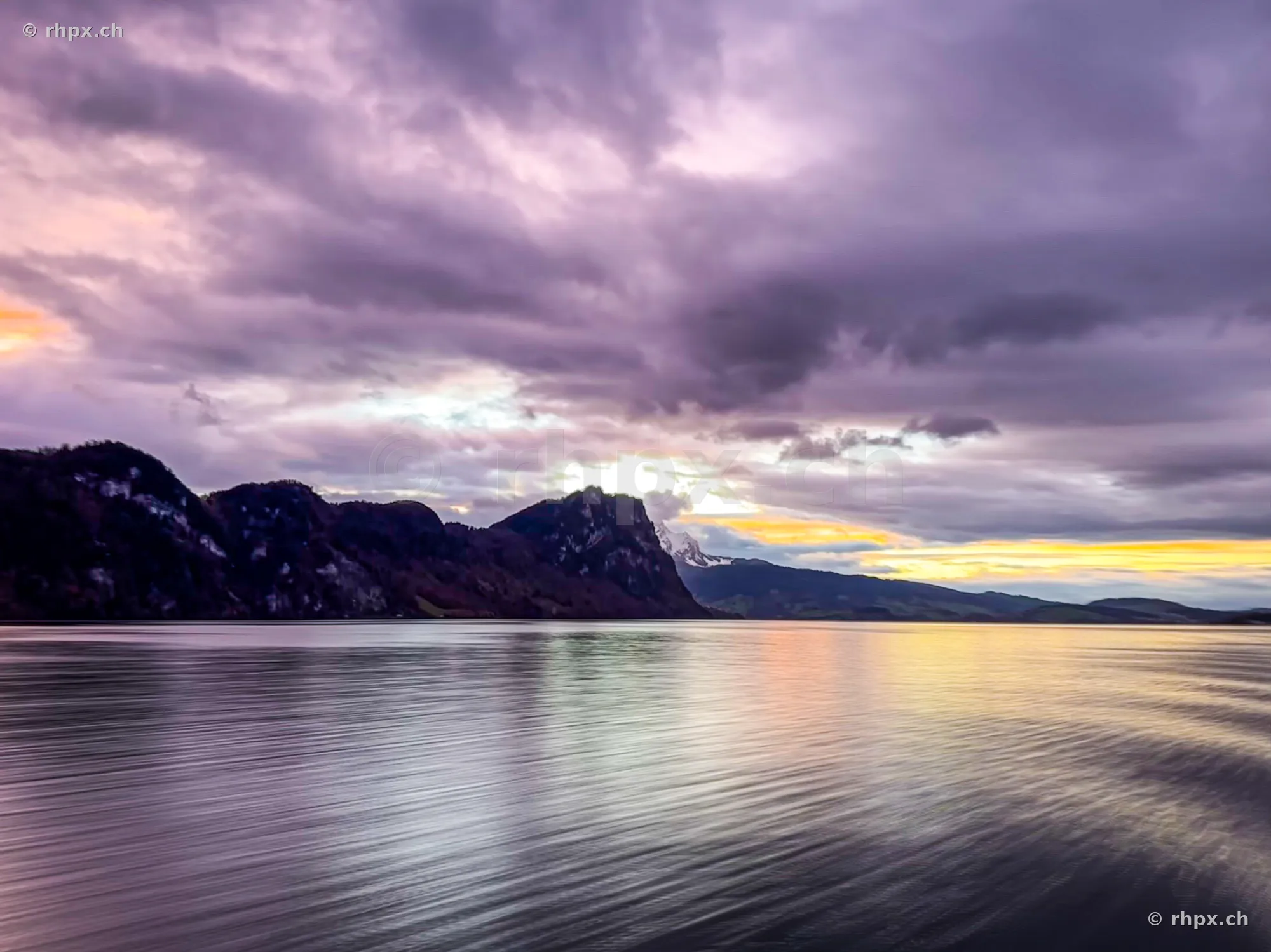 View over Lake Lucerne with the Bürgenstock cliffs under a dramatic cloudy evening sky