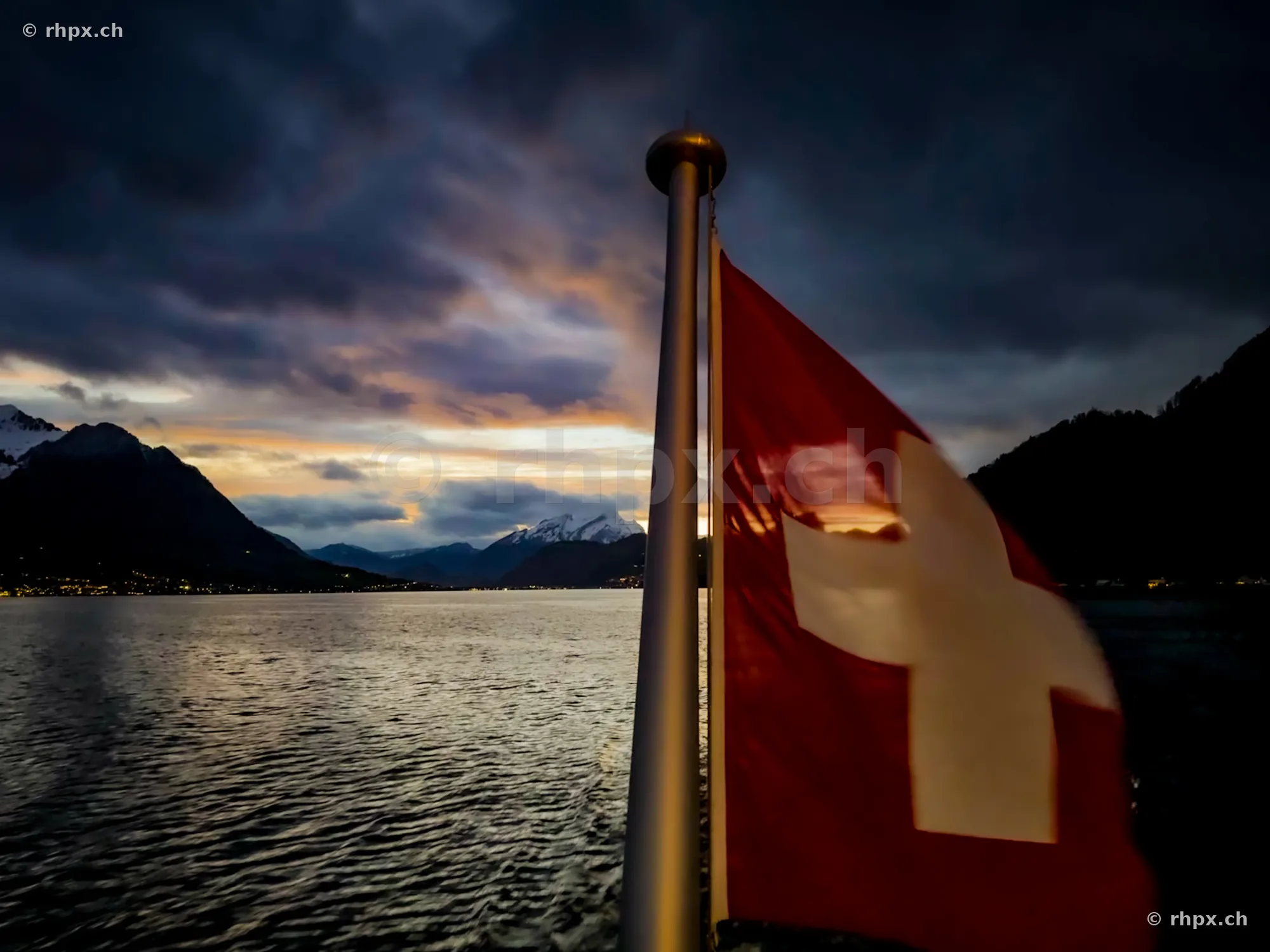 Swiss flag at the stern of a boat on Lake Lucerne with mountains in the background