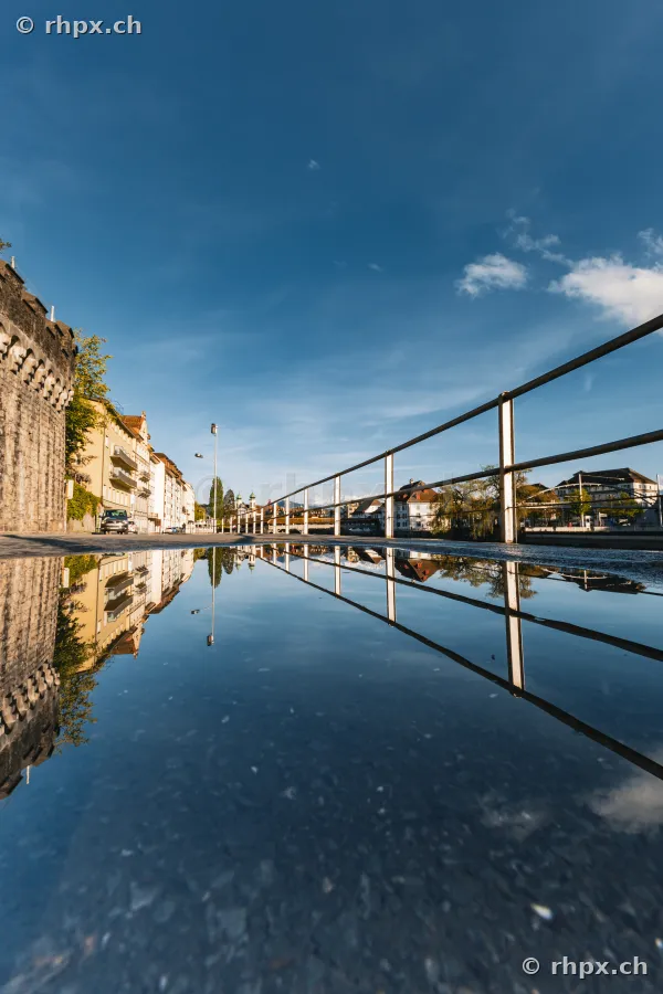 Spiegelung der Museggmauer und der Stadt Luzern in einer Pfütze auf dem Boden