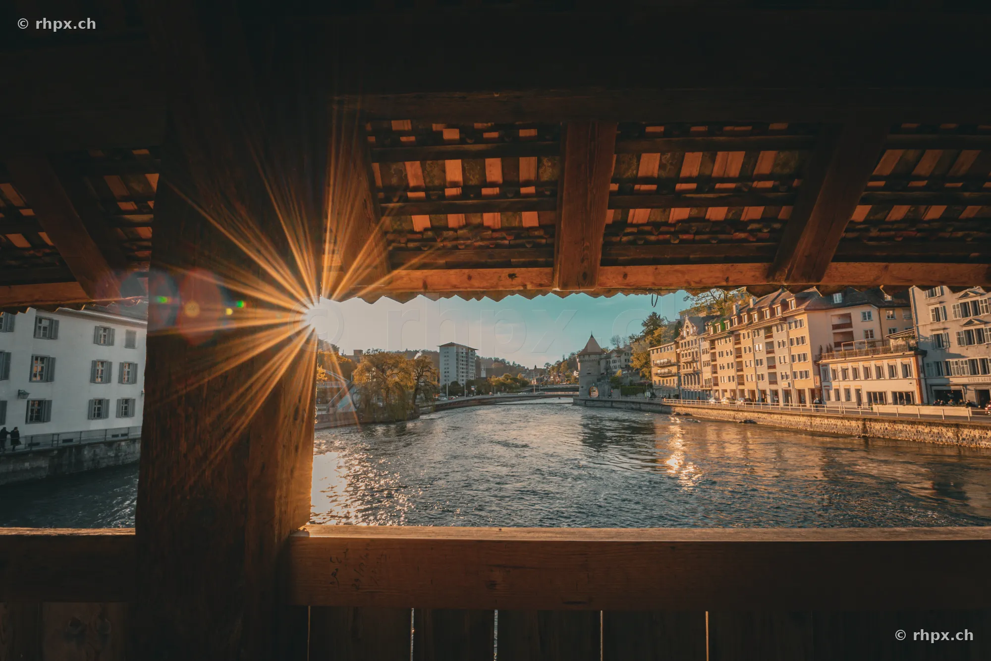 View through the wooden roof structure of the Chapel Bridge across the Reuss river in Lucerne with sunlight
