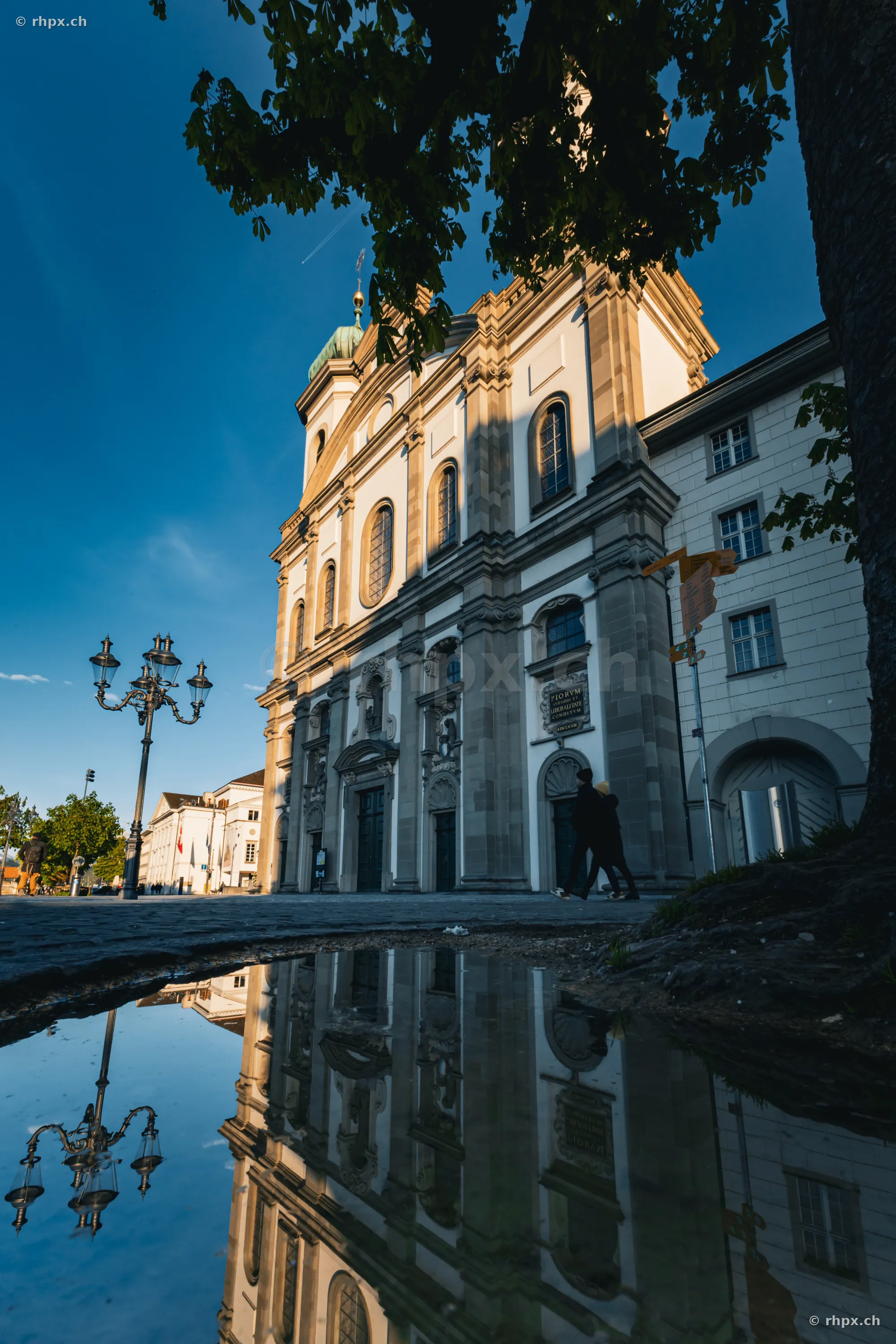 Facade of the Jesuit Church in Lucerne reflecting in a puddle