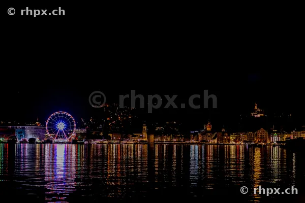 Nächtliche Ansicht des beleuchteten Riesenrads und der Silhouette der Stadt Luzern am Vierwaldstättersee