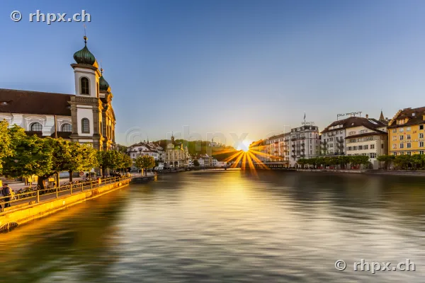 Die Jesuitenkirche und Häuserfronten entlang der Reuss in Luzern während des Sonnenuntergangs.
