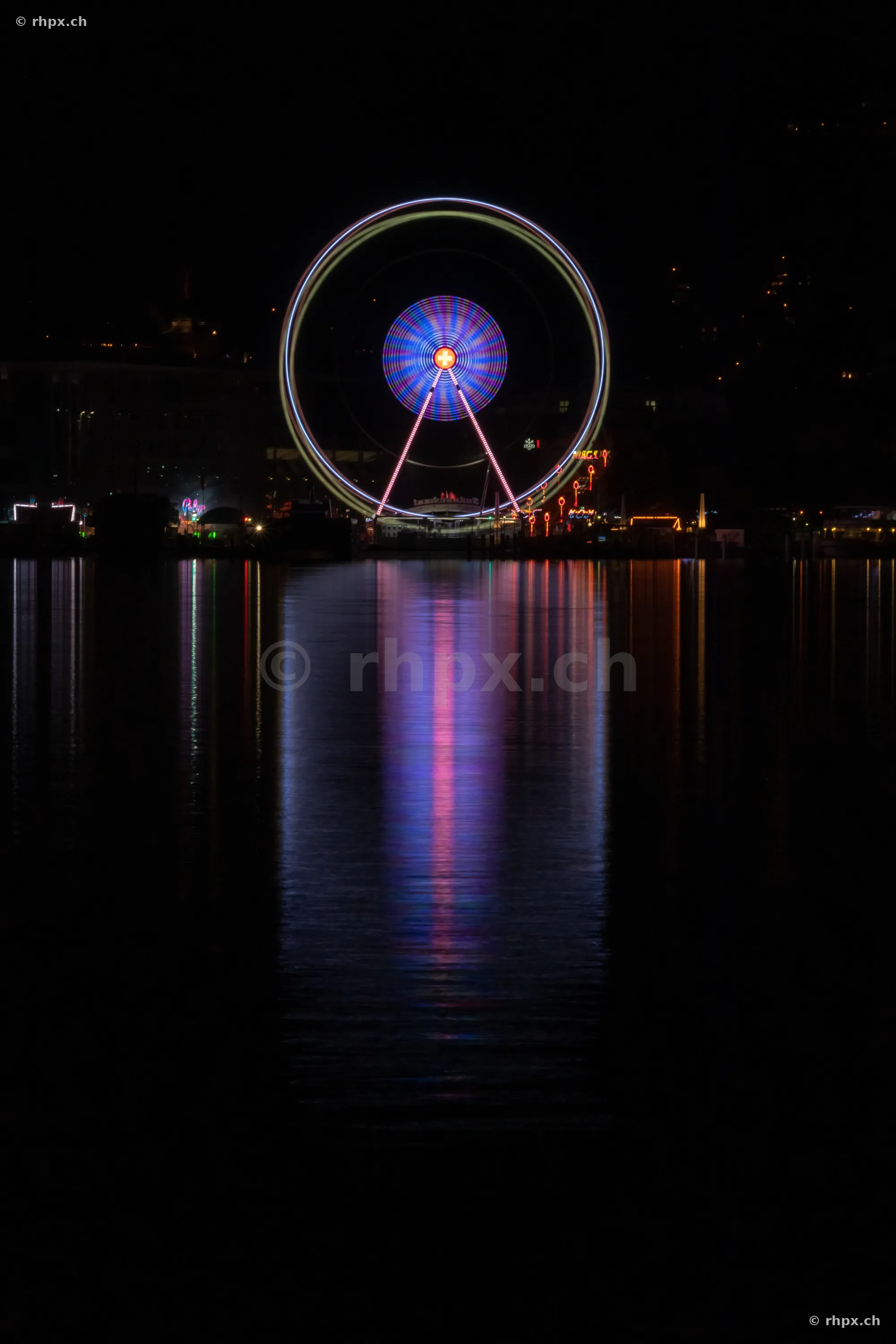 Illuminated Ferris wheel at night, reflected in Lake Lucerne in Lucerne