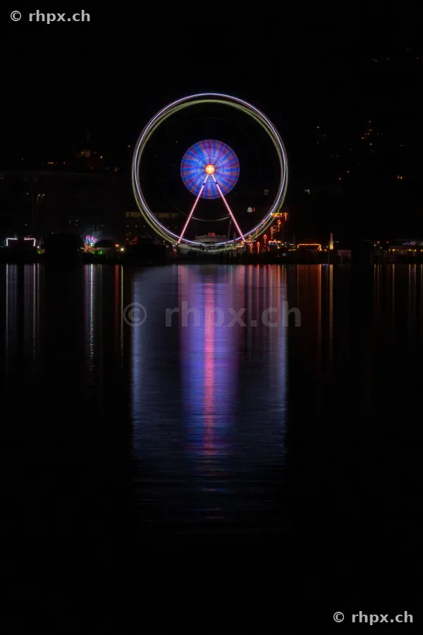 Beleuchtetes Riesenrad in der Nacht, gespiegelt im Vierwaldstättersee in Luzern