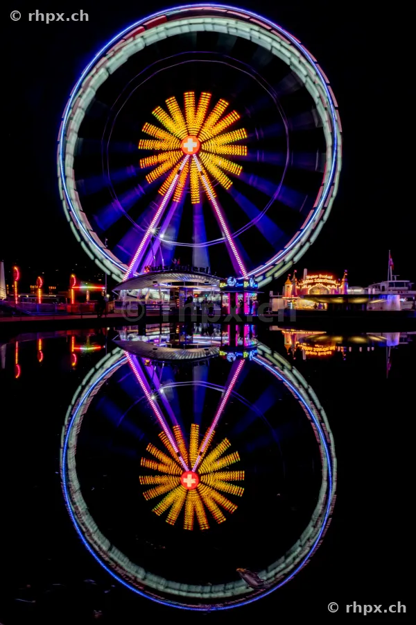 Beleuchtetes Riesenrad spiegelt sich im dunklen Wasser des Vierwaldstättersees in Luzern.