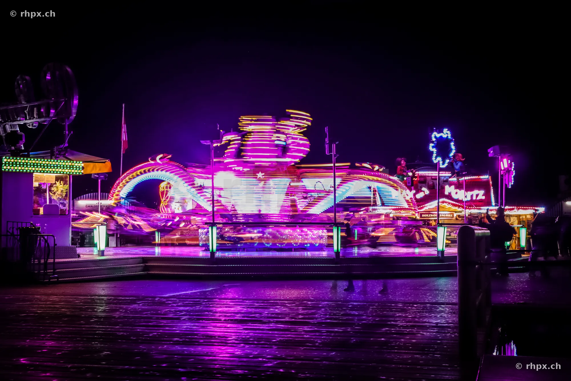 Illuminated amusement ride with light trails at a fair at night