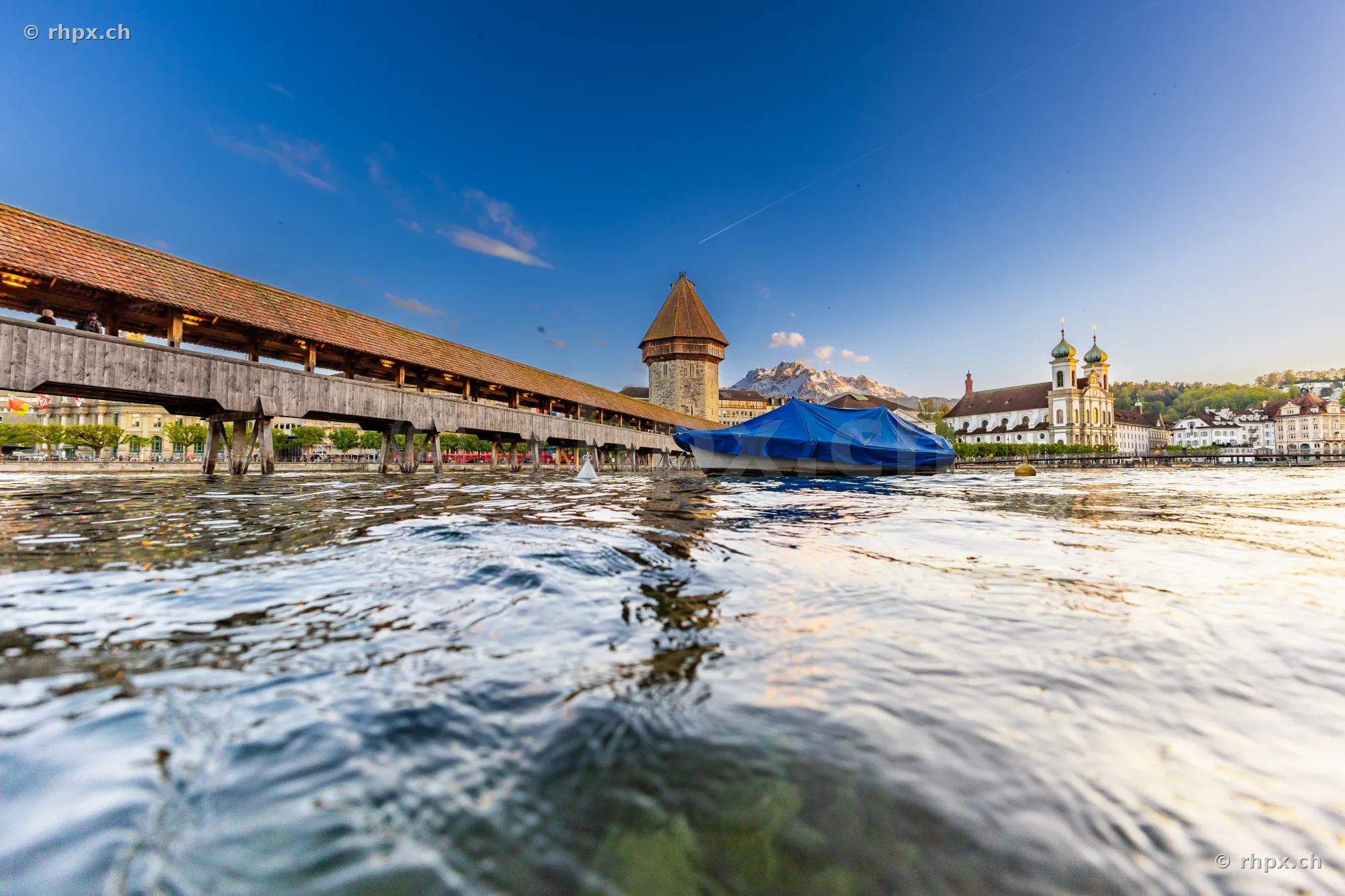 Low angle view of the Chapel Bridge and the Jesuit Church in Lucerne under a clear sky.