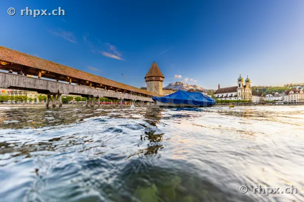 Low angle view of the Chapel Bridge and the Jesuit Church in Lucerne under a clear sky.