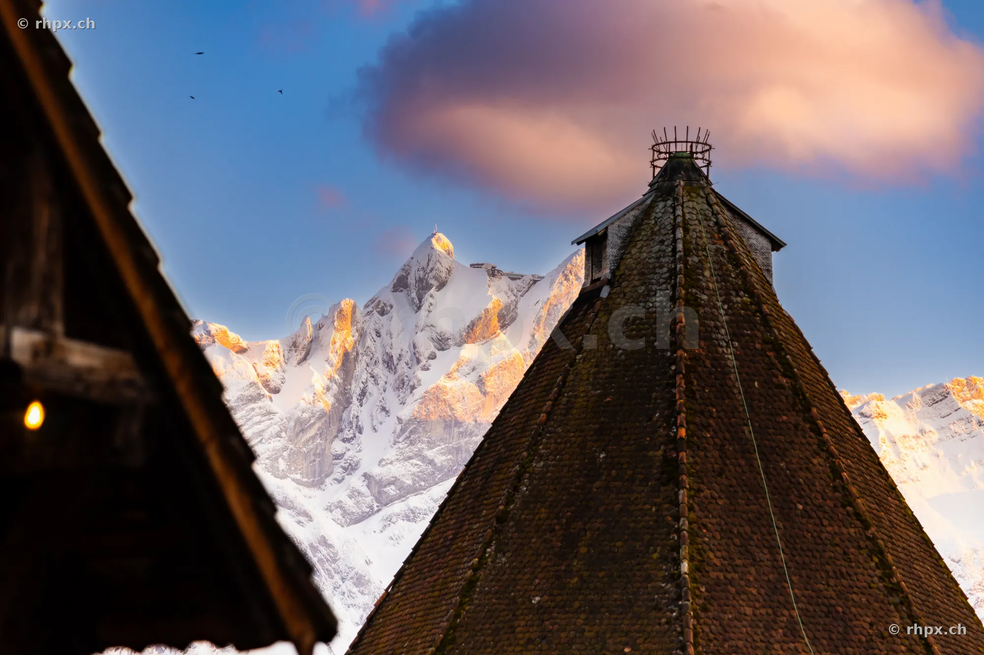 View of the old tiled roof of a Musegg wall tower in Lucerne with the snow-capped Pilatus mountain in the background