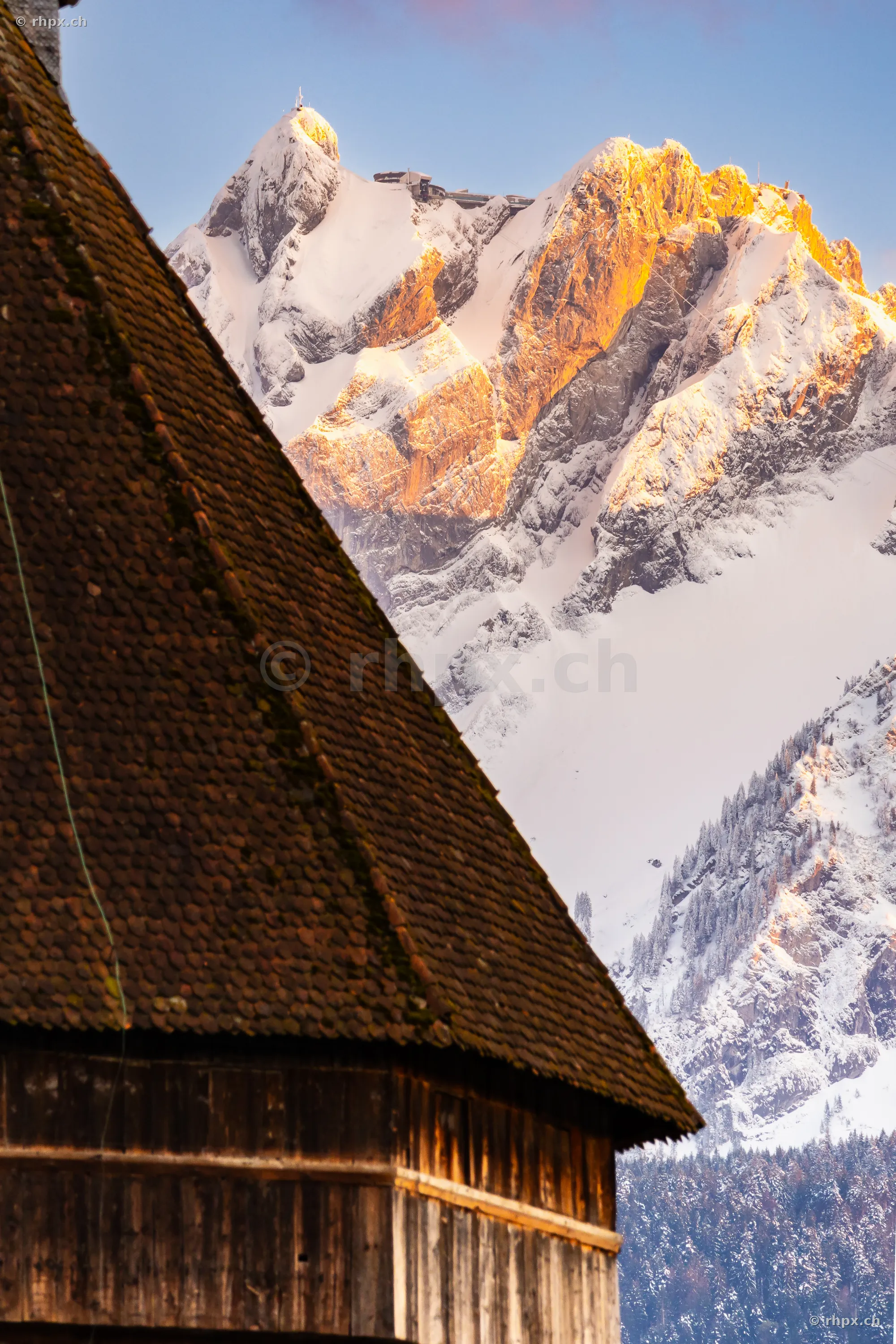 Mount Pilatus with Hotel Bellevue in evening light behind an old wooden building