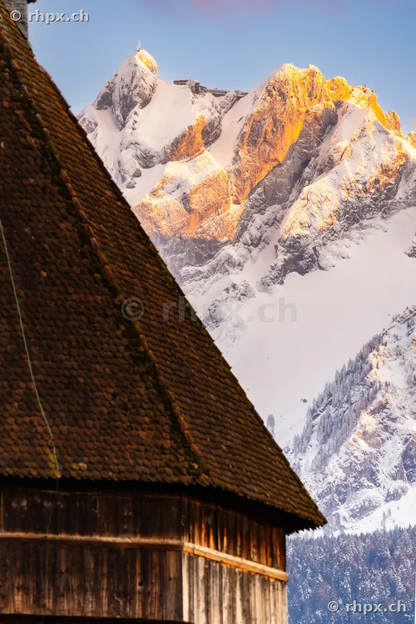 Mount Pilatus with Hotel Bellevue in evening light behind an old wooden building