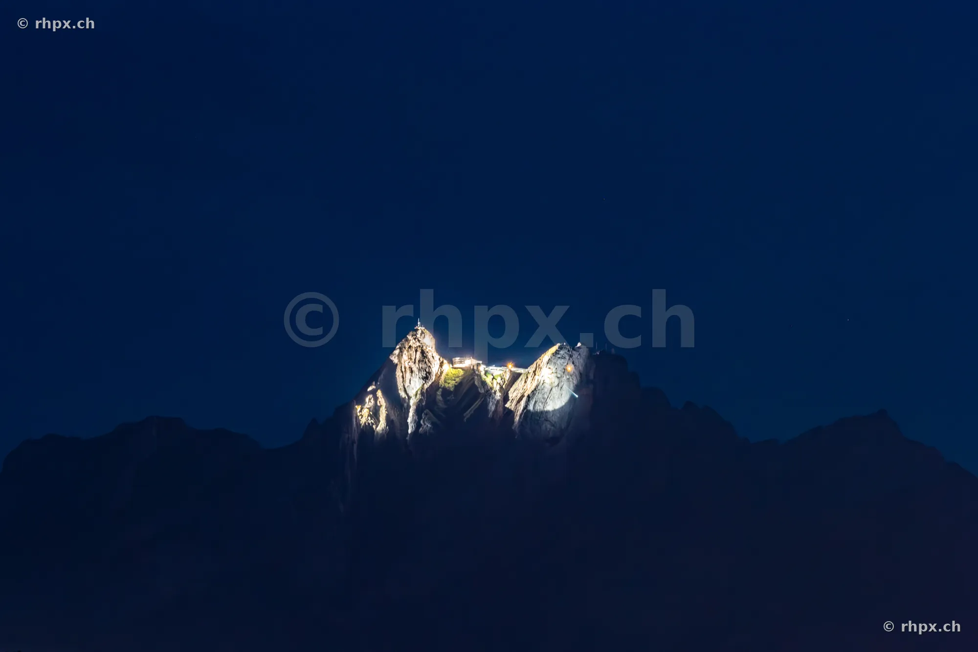 Beleuchtete Gipfelformation des Pilatus vor dunklem Nachthimmel