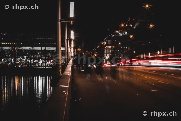 Seebrücke in Luzern bei Nacht mit vorbeifahrenden Fahrzeugen und Lichtspuren