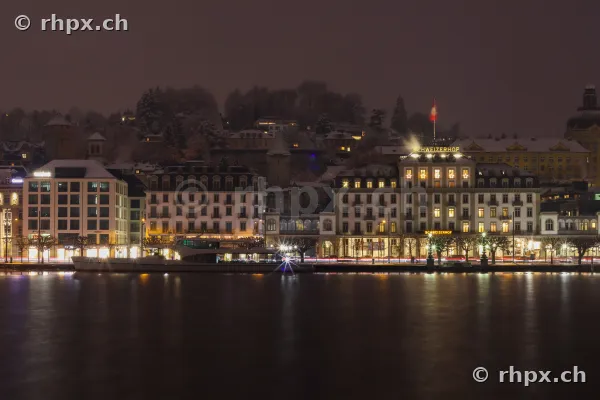 Beleuchtete Gebäude am Ufer des Vierwaldstättersees in Luzern bei Nacht und leichtem Schnee