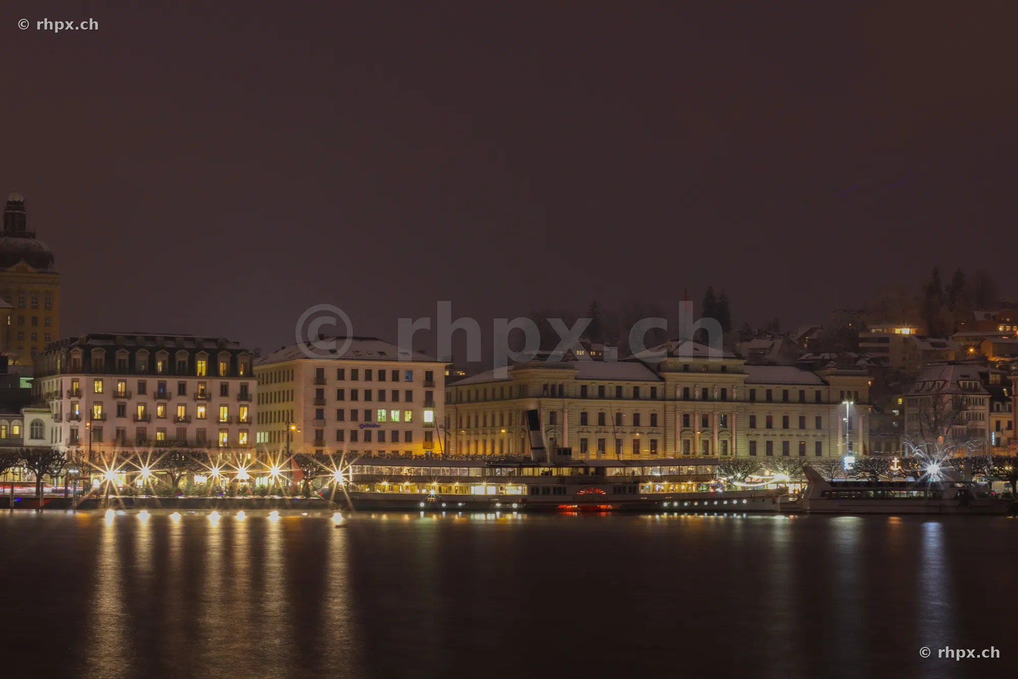 Illuminated buildings and ships on Lake Lucerne at night
