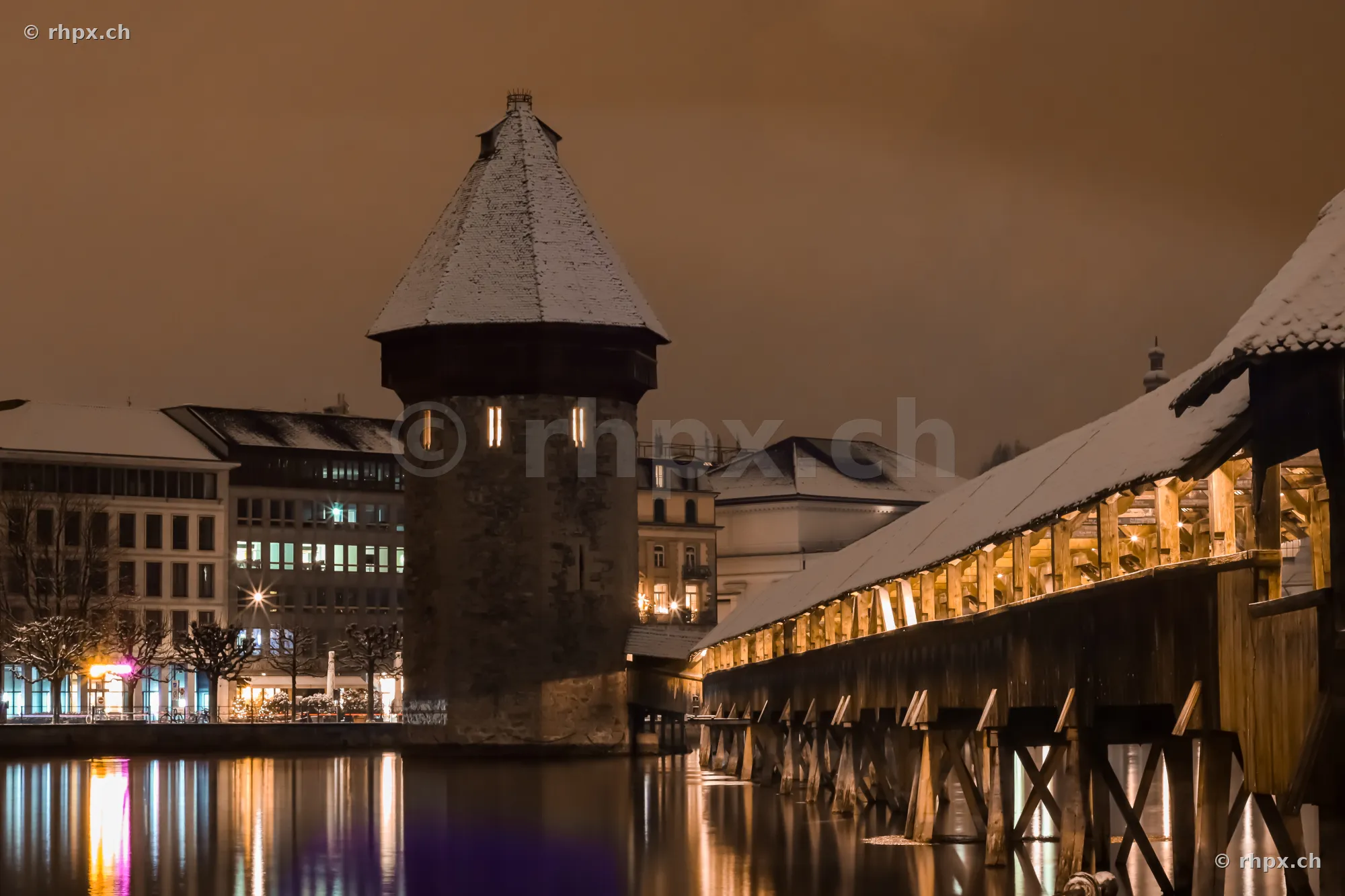 Wasserturm and Chapel Bridge in Lucerne at night with snow on the roofs