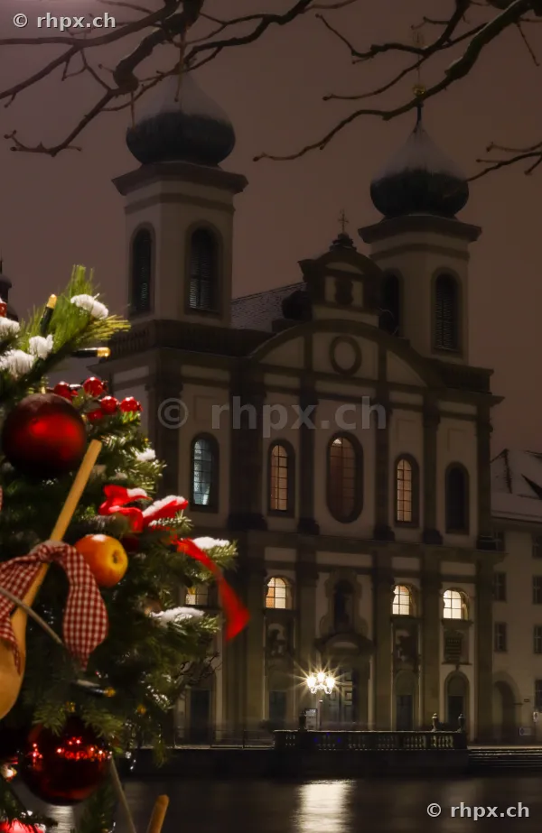 Jesuit Church in Lucerne at night with a decorated Christmas tree in the foreground