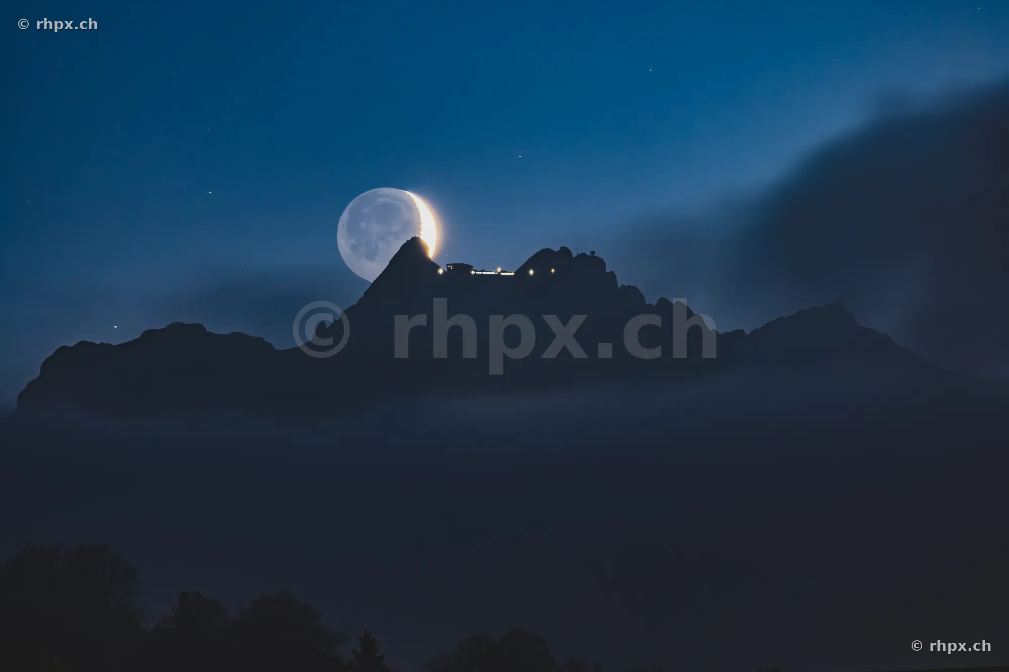 Crescent moon in the evening sky directly above the summit ridge of Mount Pilatus near Lucerne.