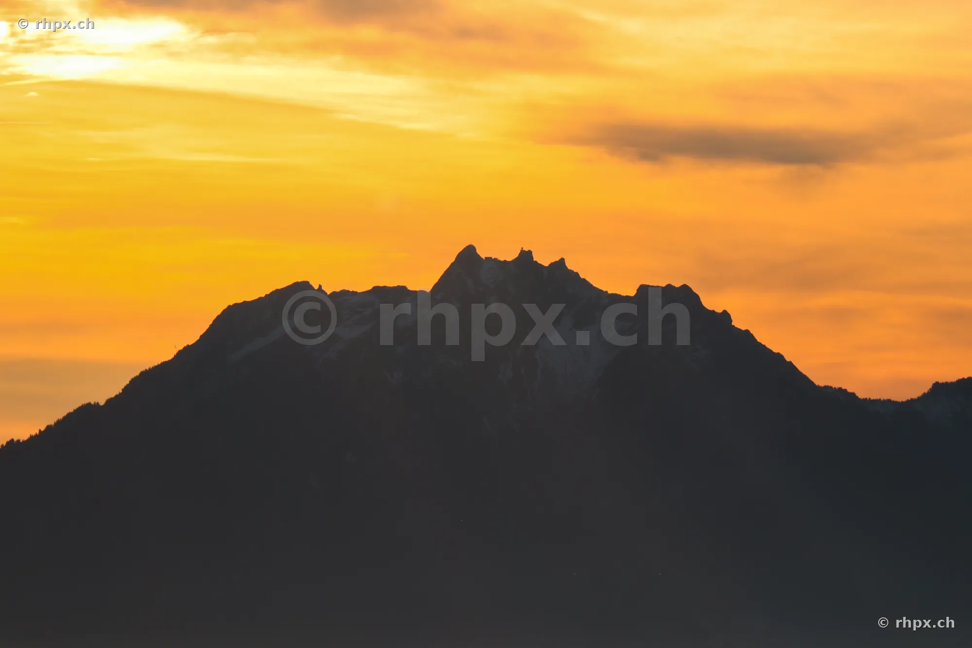 Silhouette des Berges Pilatus vor einem orangefarbenen Abendhimmel
