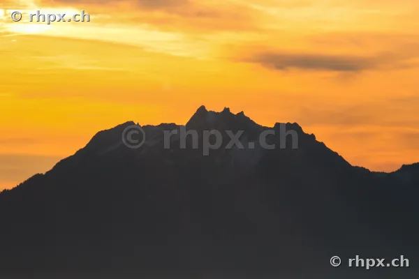 Silhouette des Berges Pilatus vor einem orangefarbenen Abendhimmel