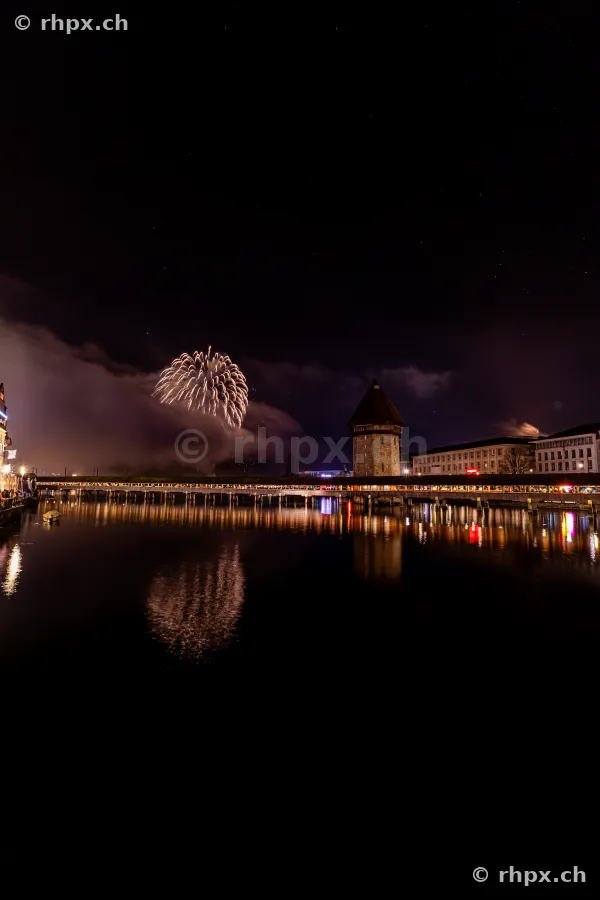 Night-time New Year fireworks over the Chapel Bridge and Wasserturm in Lucerne