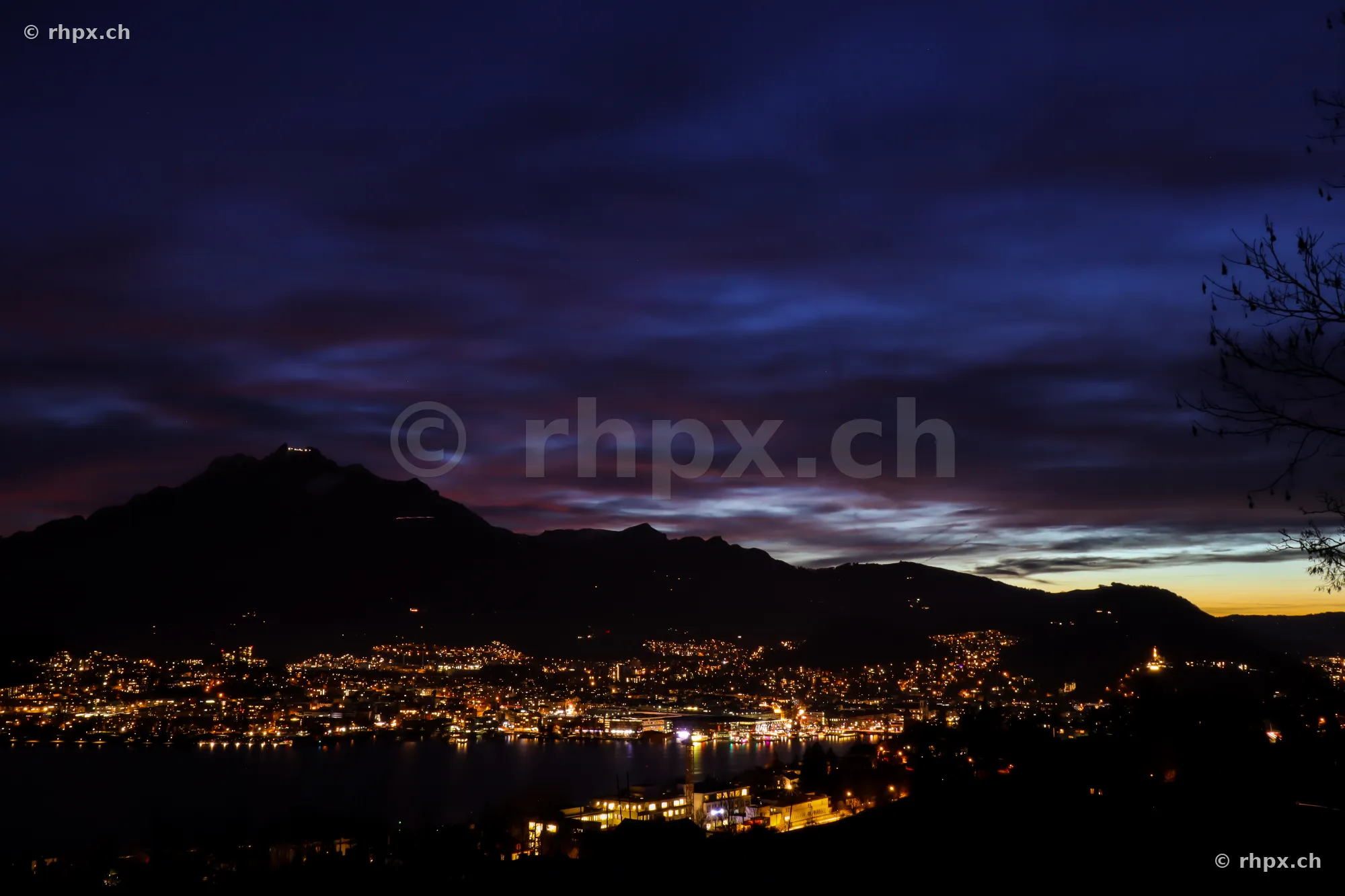 View of the city lights of Lucerne at night with Mount Pilatus in the background