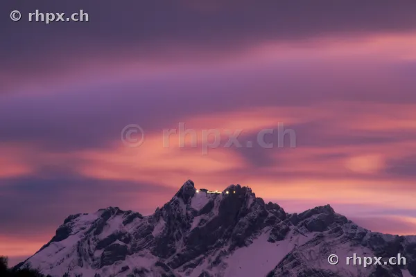 Der verschneite Gipfel des Pilatus in der Abenddämmerung mit beleuchtetem Hotel